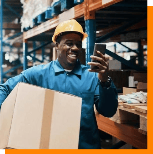 Warehouse worker smiling at phone carrying box Warehouse worker smiling at phone carrying box